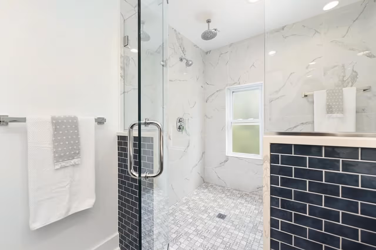 A finished walk-in shower with marble tile and a glass door