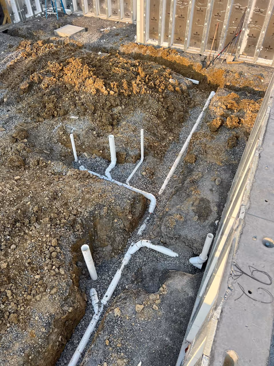 PVC drain lines roughed into the foundation trench of a new build