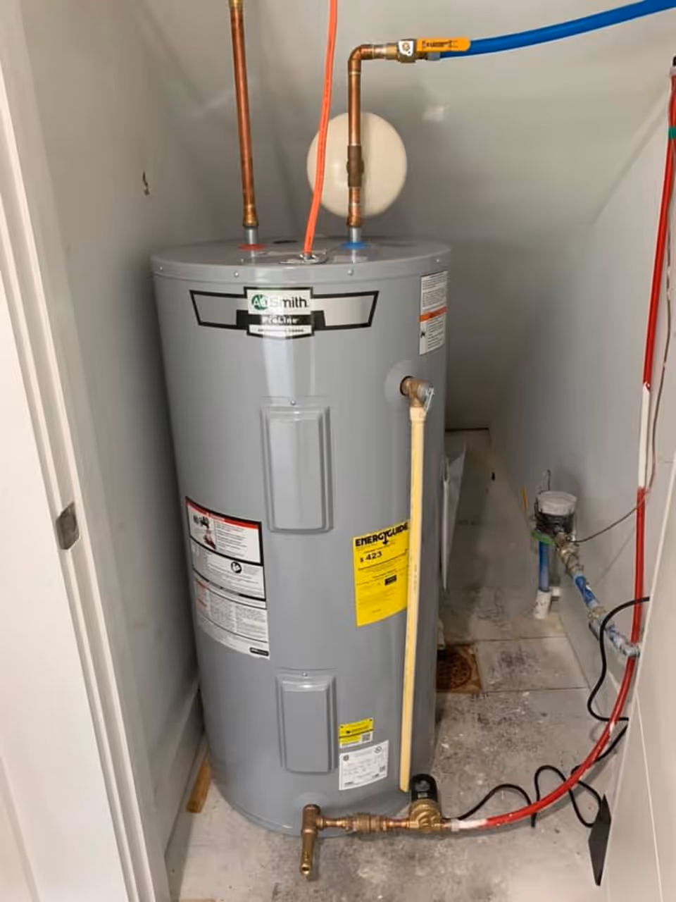 A newly installed electric water heater with copper connections